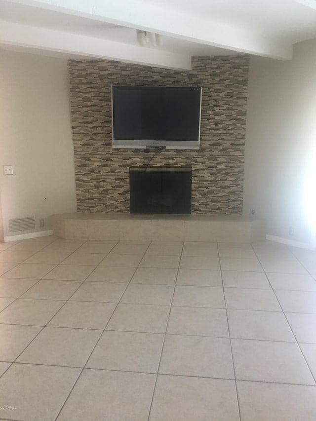 unfurnished living room with tile patterned flooring, a fireplace, visible vents, and beamed ceiling