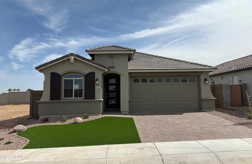 view of front of house featuring a garage, fence, decorative driveway, and stucco siding