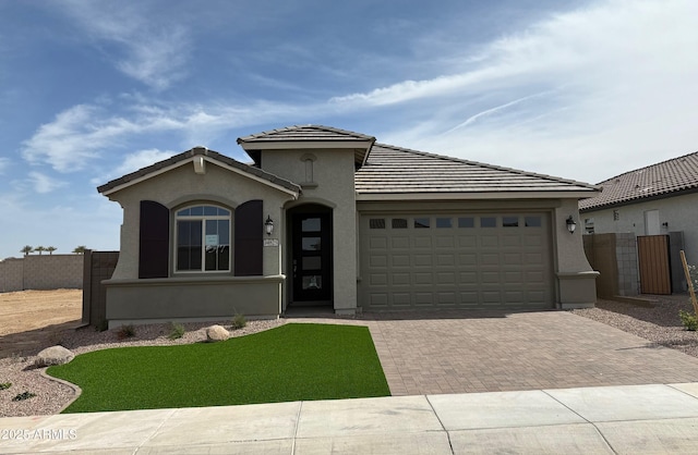 view of front of house featuring a garage, fence, decorative driveway, and stucco siding