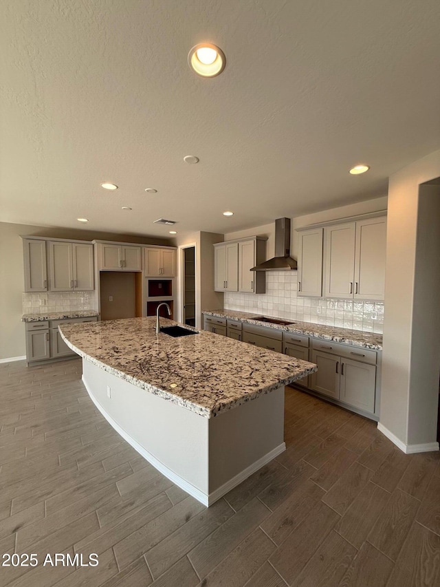 kitchen with backsplash, wood tiled floor, a sink, wall chimney exhaust hood, and black electric cooktop