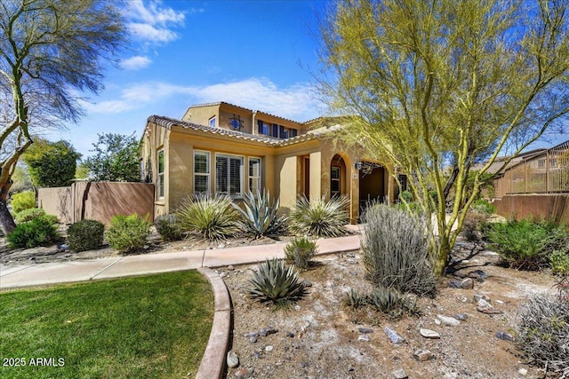mediterranean / spanish house with fence, stucco siding, and a tiled roof