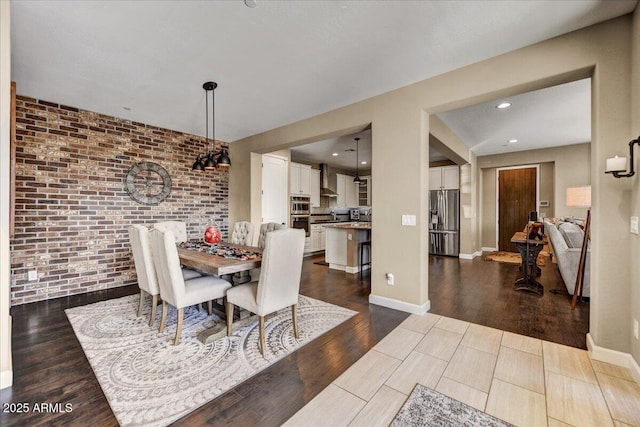 dining room with recessed lighting, baseboards, brick wall, and dark wood finished floors