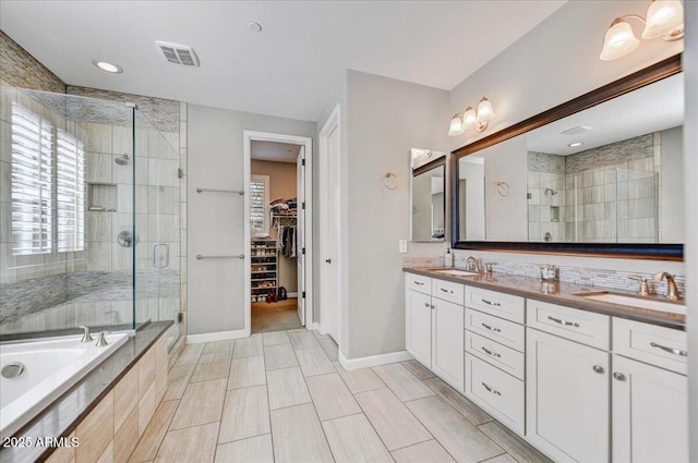 bathroom with a sink, double vanity, a shower stall, and visible vents