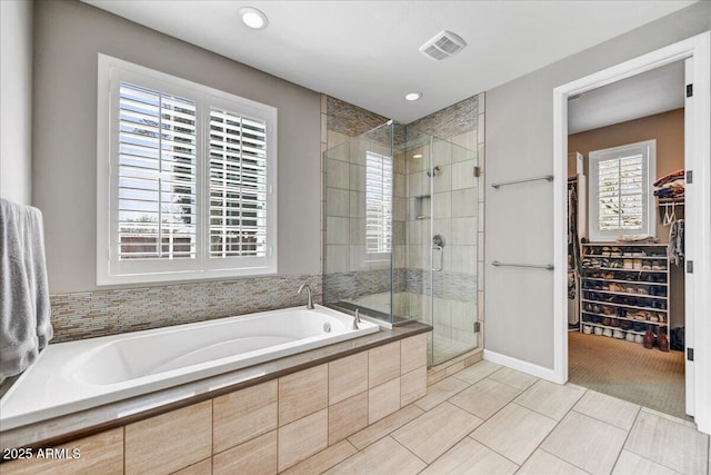 bathroom with visible vents, a shower stall, recessed lighting, a garden tub, and a walk in closet