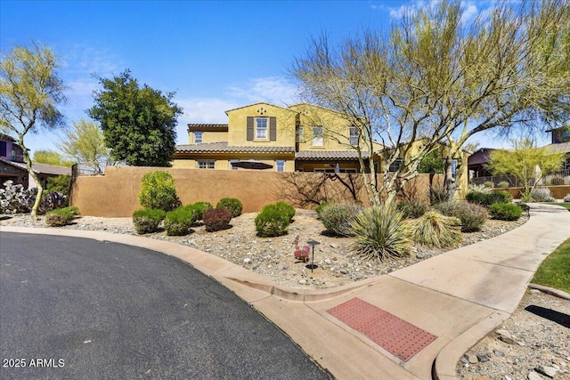 mediterranean / spanish-style house with a tile roof, a fenced front yard, and stucco siding