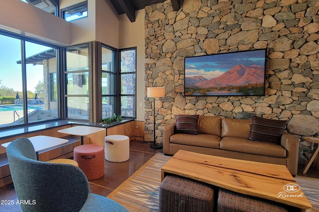 living area featuring a high ceiling, a healthy amount of sunlight, and beamed ceiling
