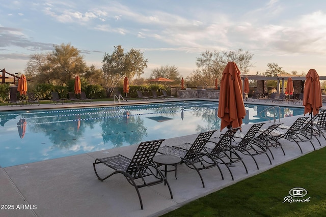 pool at dusk featuring a community pool and a patio