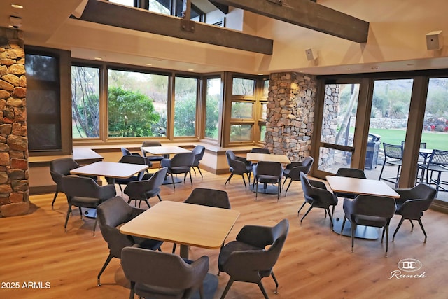 dining space featuring a towering ceiling, light wood-style flooring, and beam ceiling