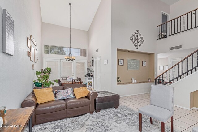 living room featuring an inviting chandelier, a towering ceiling, tile patterned flooring, and visible vents