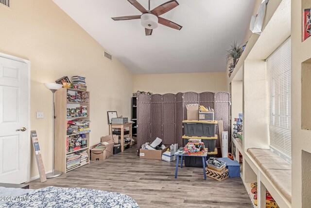 bedroom with ceiling fan, visible vents, wood finished floors, and vaulted ceiling