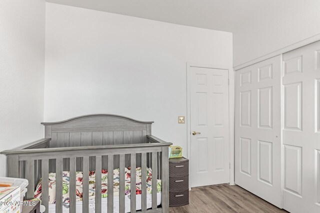 bedroom with a crib and wood finished floors