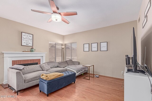 living area with visible vents, a ceiling fan, light wood-style flooring, and a brick fireplace