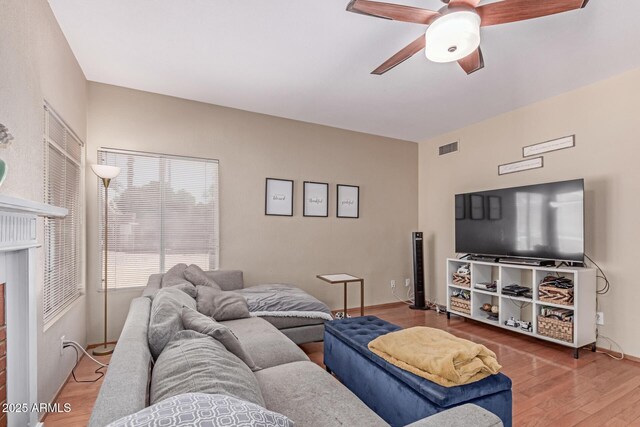 living area with visible vents, a ceiling fan, and wood finished floors