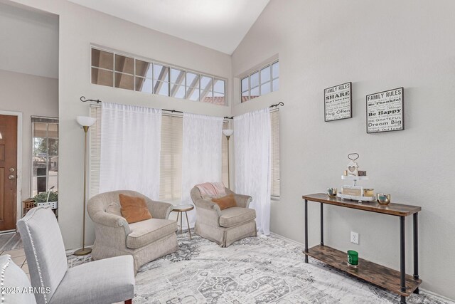 sitting room with high vaulted ceiling and baseboards