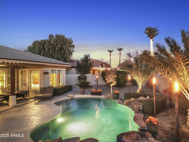 pool at dusk featuring a patio