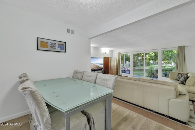 dining space with a textured ceiling and light hardwood / wood-style floors