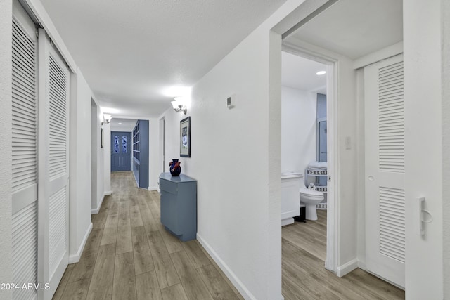 hallway featuring a textured ceiling and light hardwood / wood-style flooring