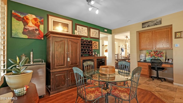 dining area with beverage cooler, baseboards, and light wood-style floors