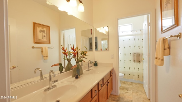 full bath featuring double vanity, curtained shower, toilet, and a sink