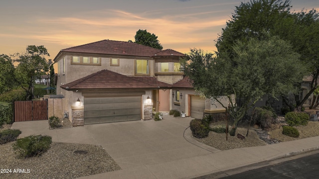 view of front of property with a tile roof, stucco siding, a garage, driveway, and a gate