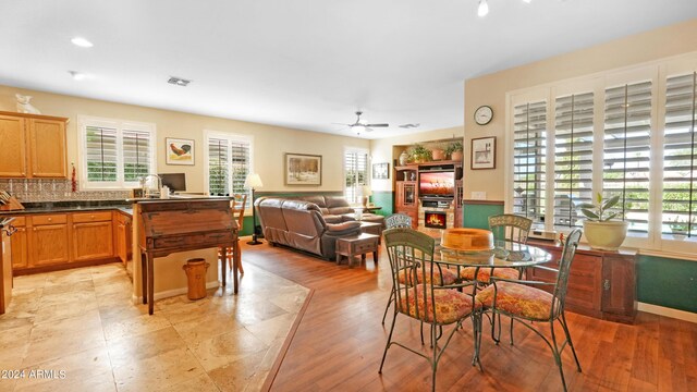 living room featuring ceiling fan, wood-type flooring, and a stone fireplace