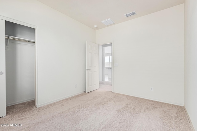 unfurnished bedroom featuring light carpet and a closet