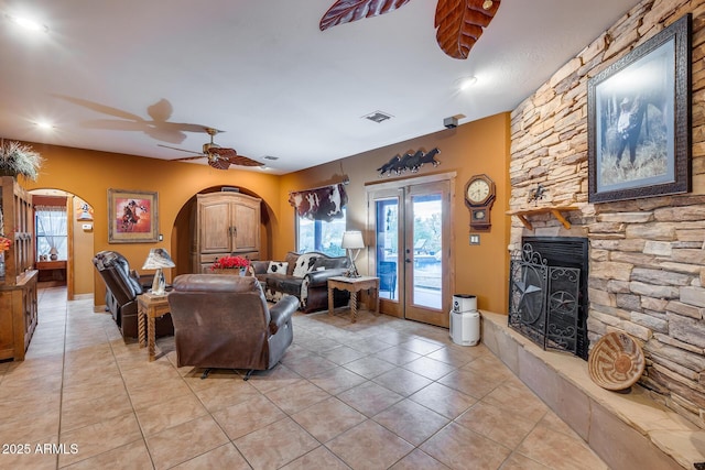 living room with a fireplace, french doors, ceiling fan, and light tile patterned flooring