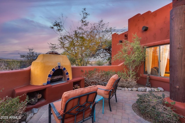 patio terrace at dusk featuring an outdoor fireplace