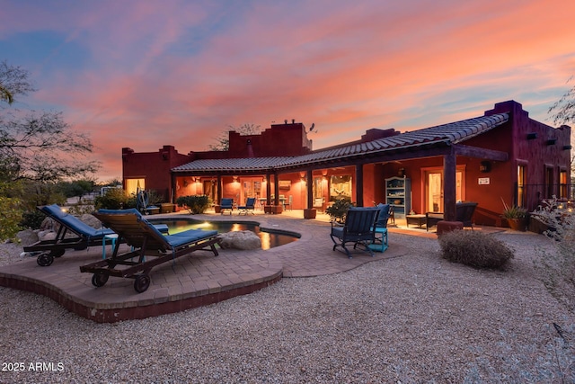 back house at dusk featuring a patio