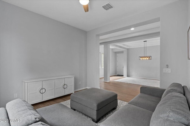 living area featuring visible vents, baseboards, ceiling fan, and dark wood-style flooring