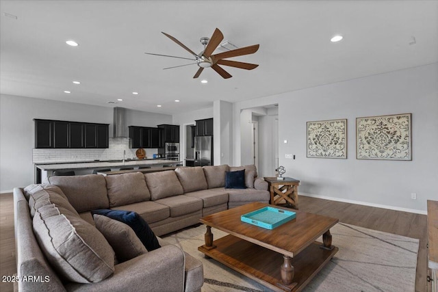 living room with recessed lighting, a ceiling fan, light wood-style floors, and baseboards