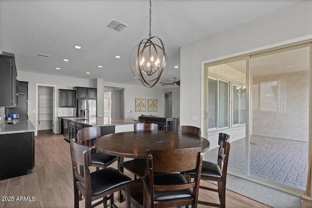 dining area with recessed lighting, visible vents, light wood-style floors, and ceiling fan with notable chandelier