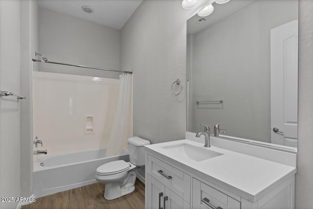 full bath featuring shower / bath combo with shower curtain, toilet, wood finished floors, vanity, and a textured wall