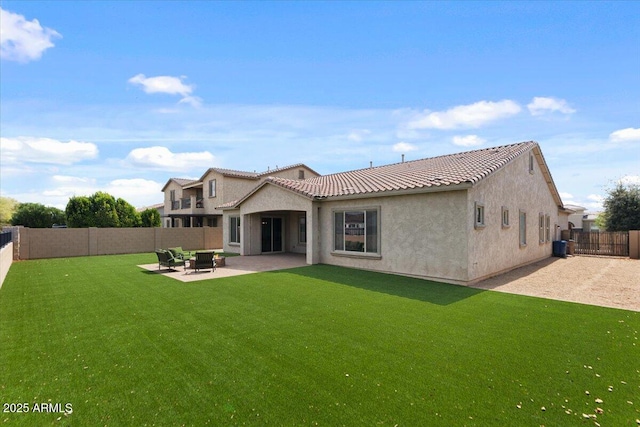 back of property with stucco siding, a tile roof, a fenced backyard, a yard, and a patio area