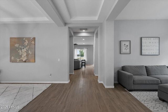 living room featuring a raised ceiling, recessed lighting, wood finished floors, and baseboards