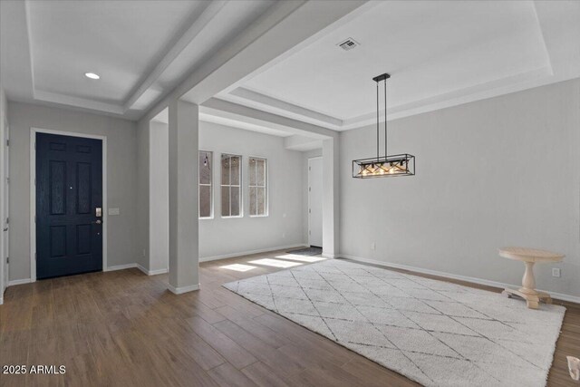 entryway featuring a tray ceiling, visible vents, and wood finished floors