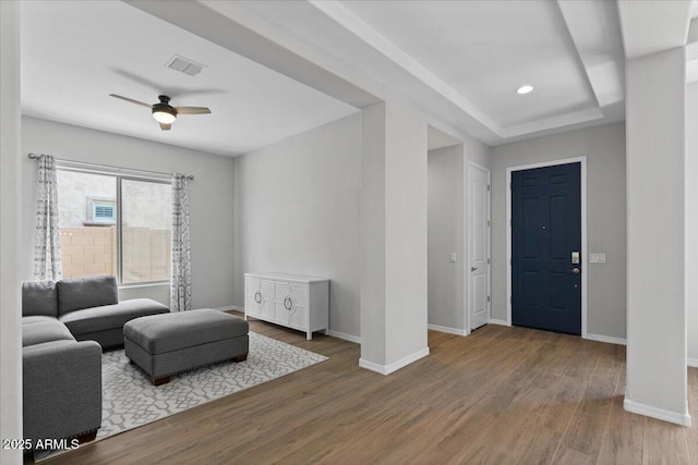 living area featuring visible vents, baseboards, ceiling fan, and wood finished floors