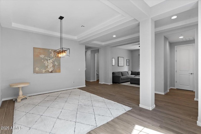 interior space featuring recessed lighting, a tray ceiling, baseboards, and wood finished floors