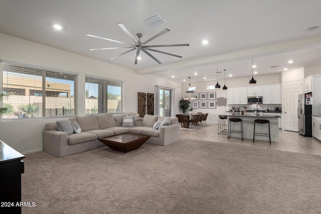 carpeted living room featuring ceiling fan and sink