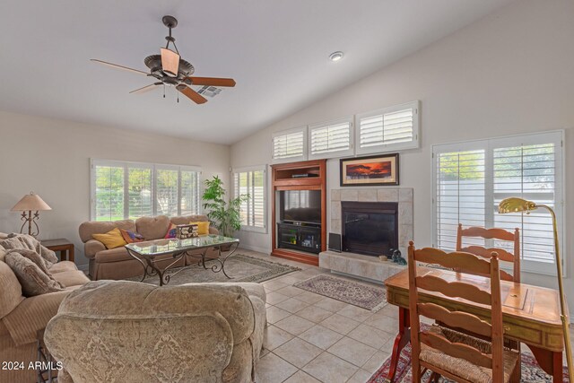 tiled living room with high vaulted ceiling, a tiled fireplace, ceiling fan, and a healthy amount of sunlight