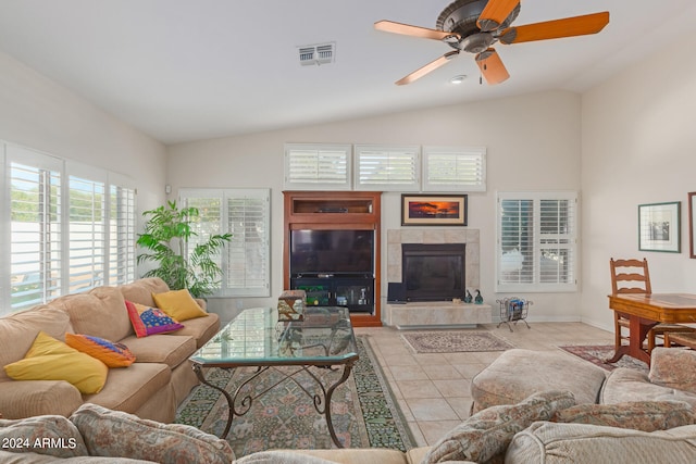 living room featuring ceiling fan, light tile patterned flooring, vaulted ceiling, and a tile fireplace