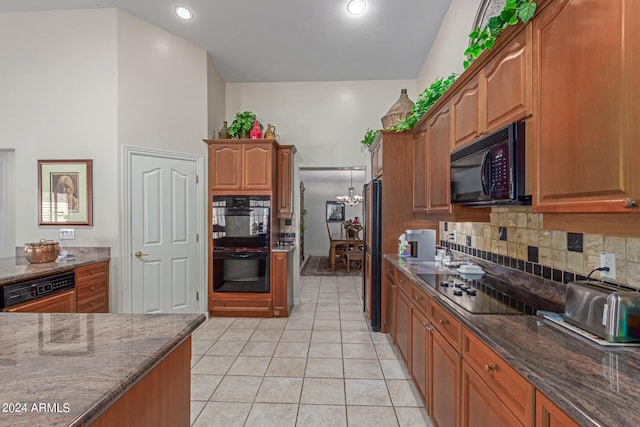 kitchen featuring a notable chandelier, black appliances, backsplash, and dark stone counters