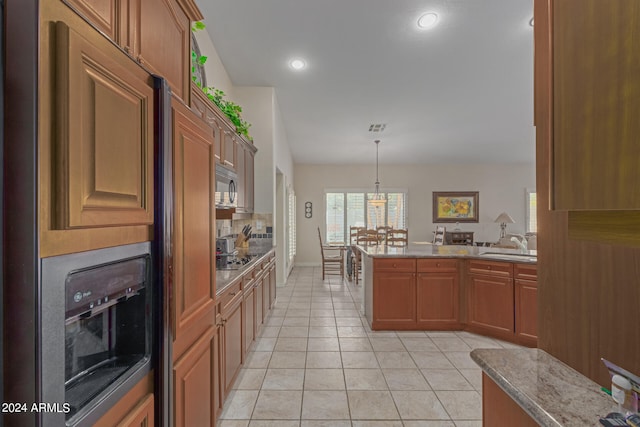 kitchen with kitchen peninsula, light tile patterned floors, black stovetop, decorative light fixtures, and sink