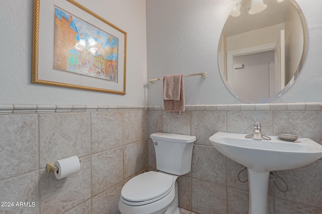 bathroom featuring tile walls and toilet