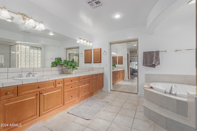 bathroom featuring tiled tub, vanity, and tile patterned flooring