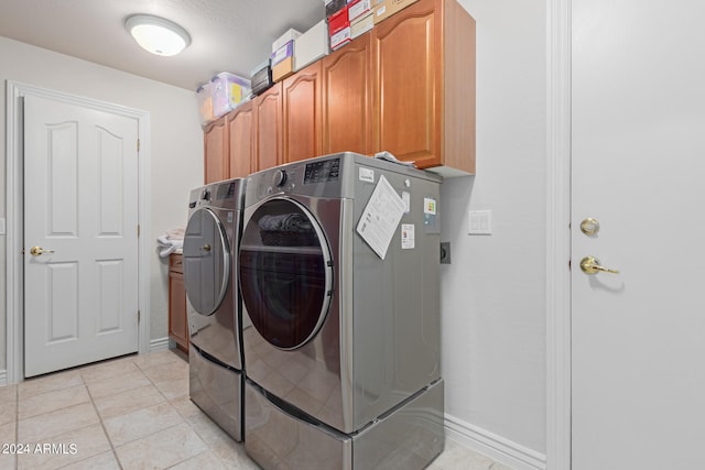 washroom featuring cabinets, light tile patterned floors, and washer and dryer