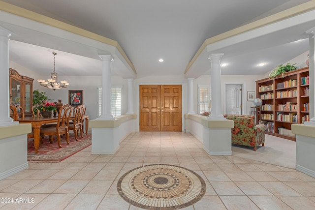 foyer featuring a wealth of natural light, vaulted ceiling, a chandelier, and ornate columns