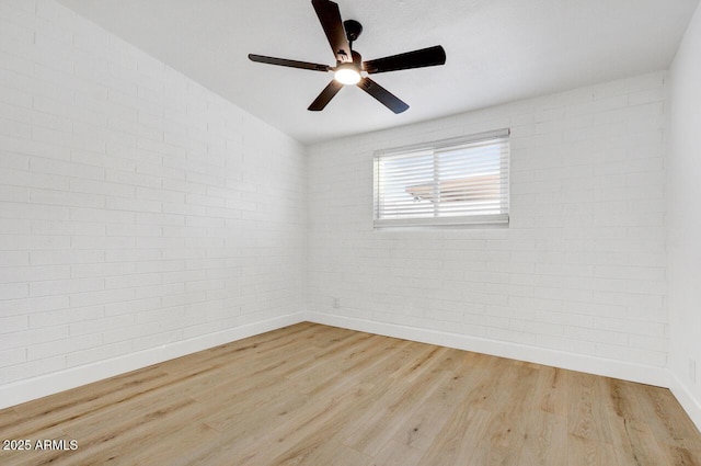 empty room featuring ceiling fan, light hardwood / wood-style floors, lofted ceiling, and brick wall