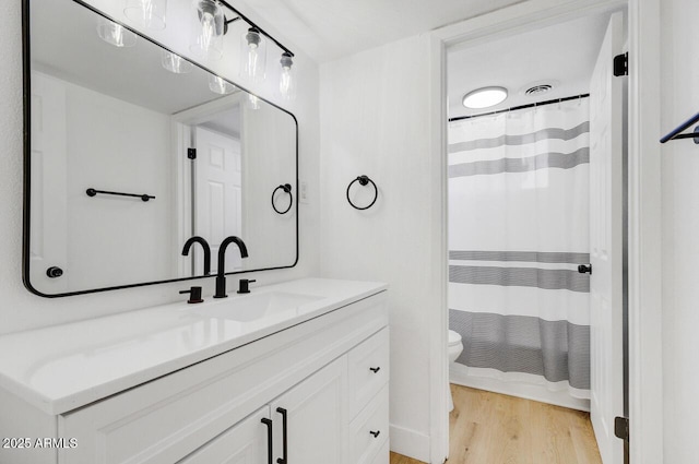 bathroom with toilet, vanity, and hardwood / wood-style flooring