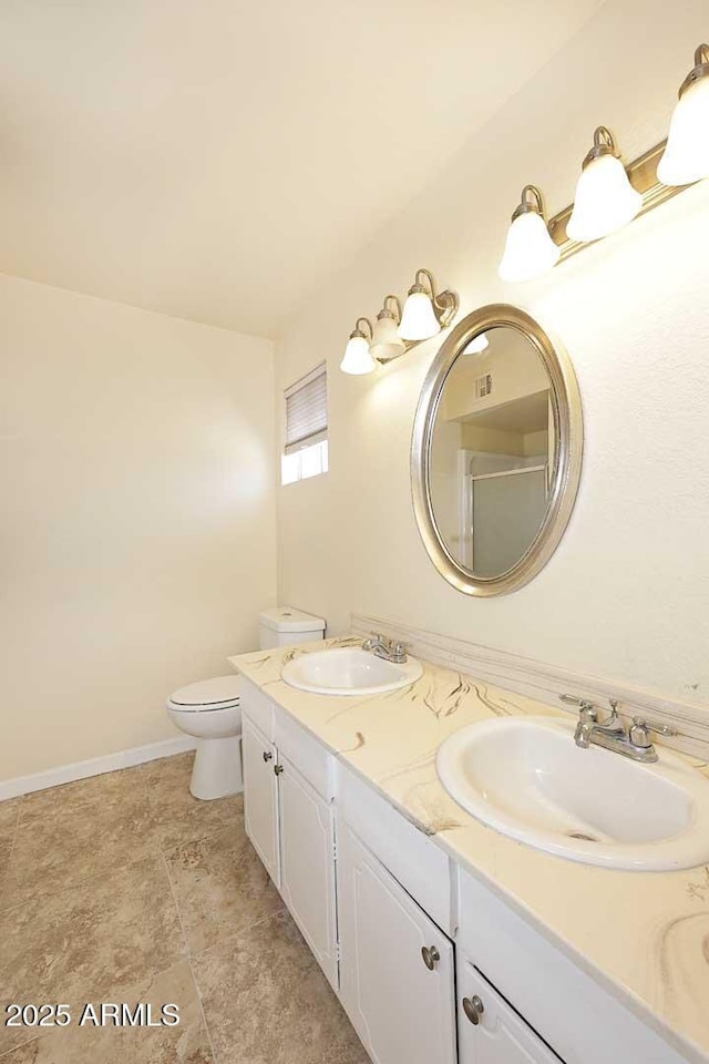 full bath featuring double vanity, a sink, toilet, and baseboards